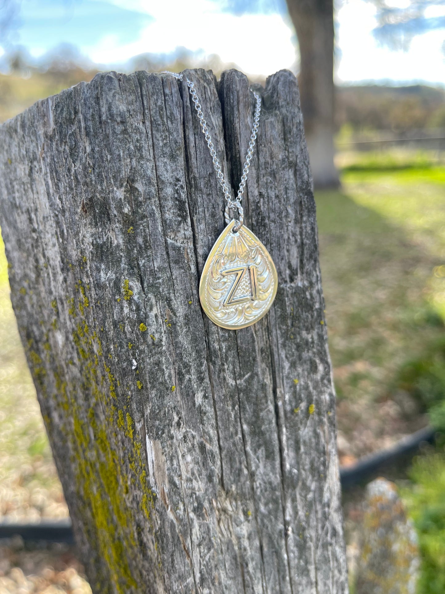 sterling silver brand on pendant with chain on fencepost 