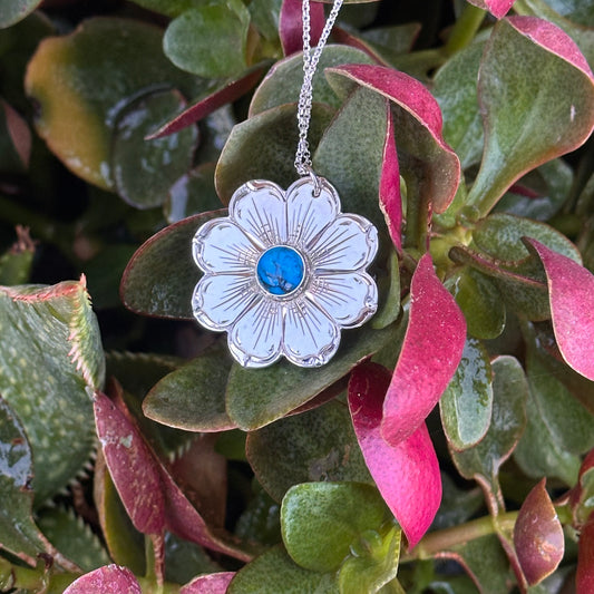 sterling silver flower pendant with turquoise stone in a bed of succulents