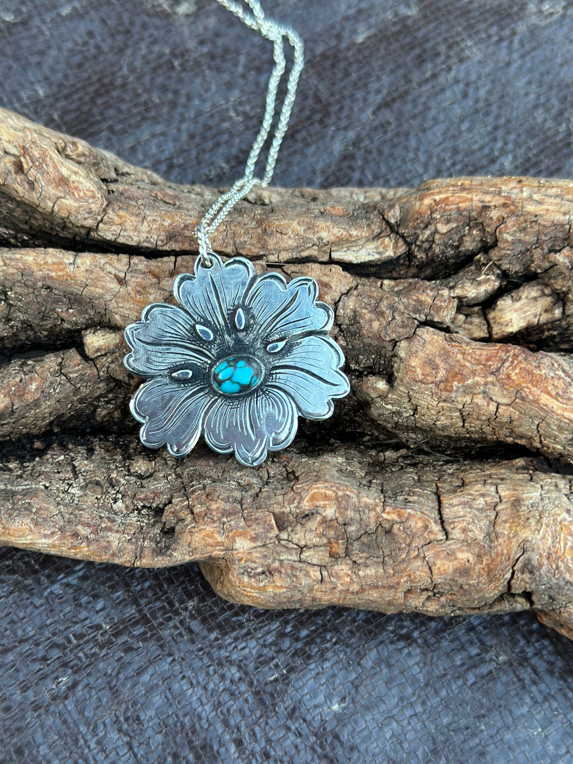sterling silver flower pendant on a piece of wood