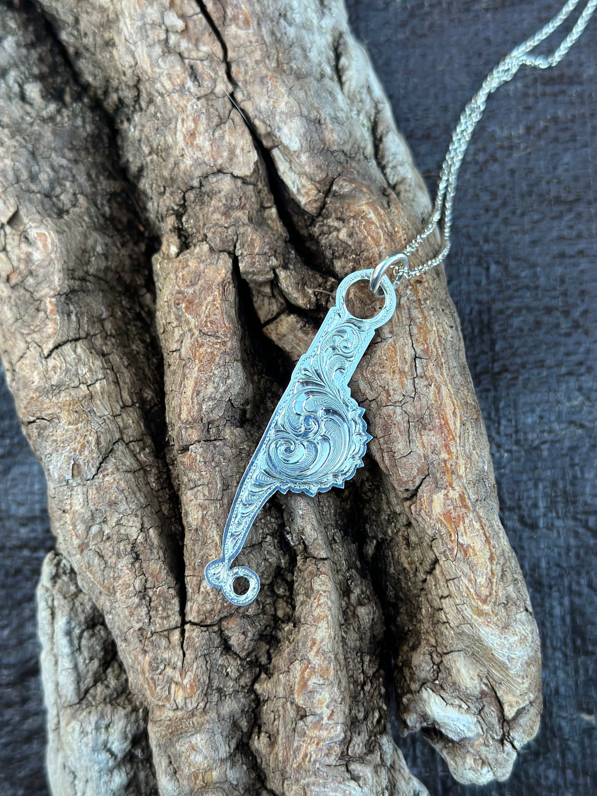 sterling silver bit cheek necklace on a piece of wood