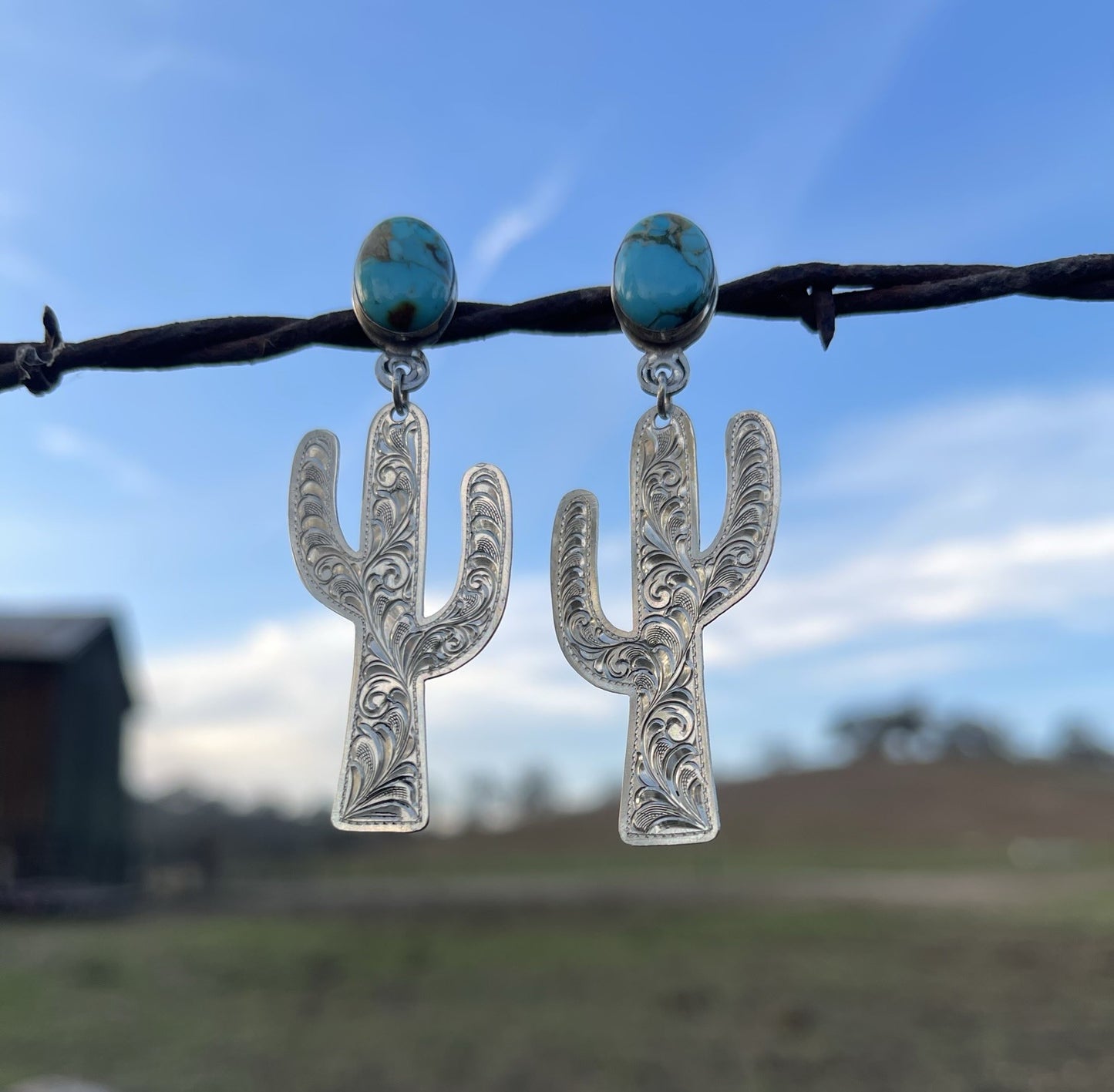 close up of sterling silver hand engraved cactus earrings with gold canyon turquoise cabochans, post eaerrings